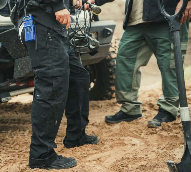 Two men attach a winch to the front of an off-road vehicle
