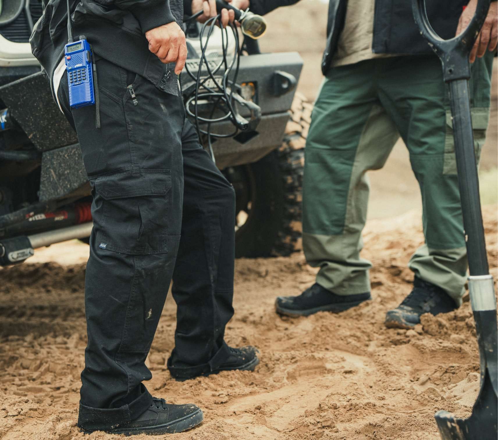 Two men attach a winch to the front of an off-road vehicle