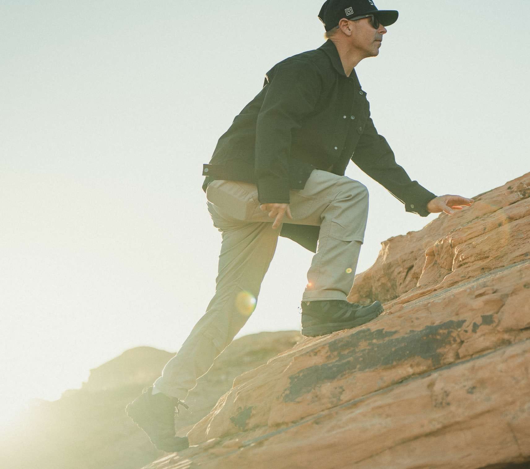 Man climbs a hill wearing the Industry Pant