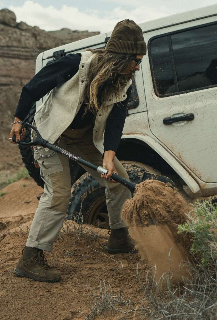 Woman in a bandana and Rosser Jacket stands beside an off-road vehicle