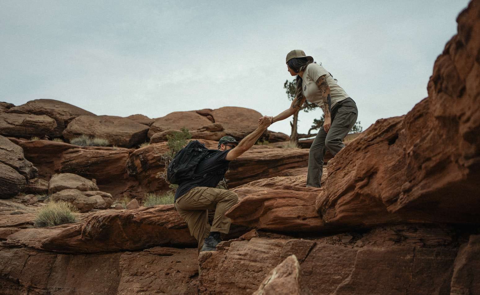 A woman and a man climb up a rocky area