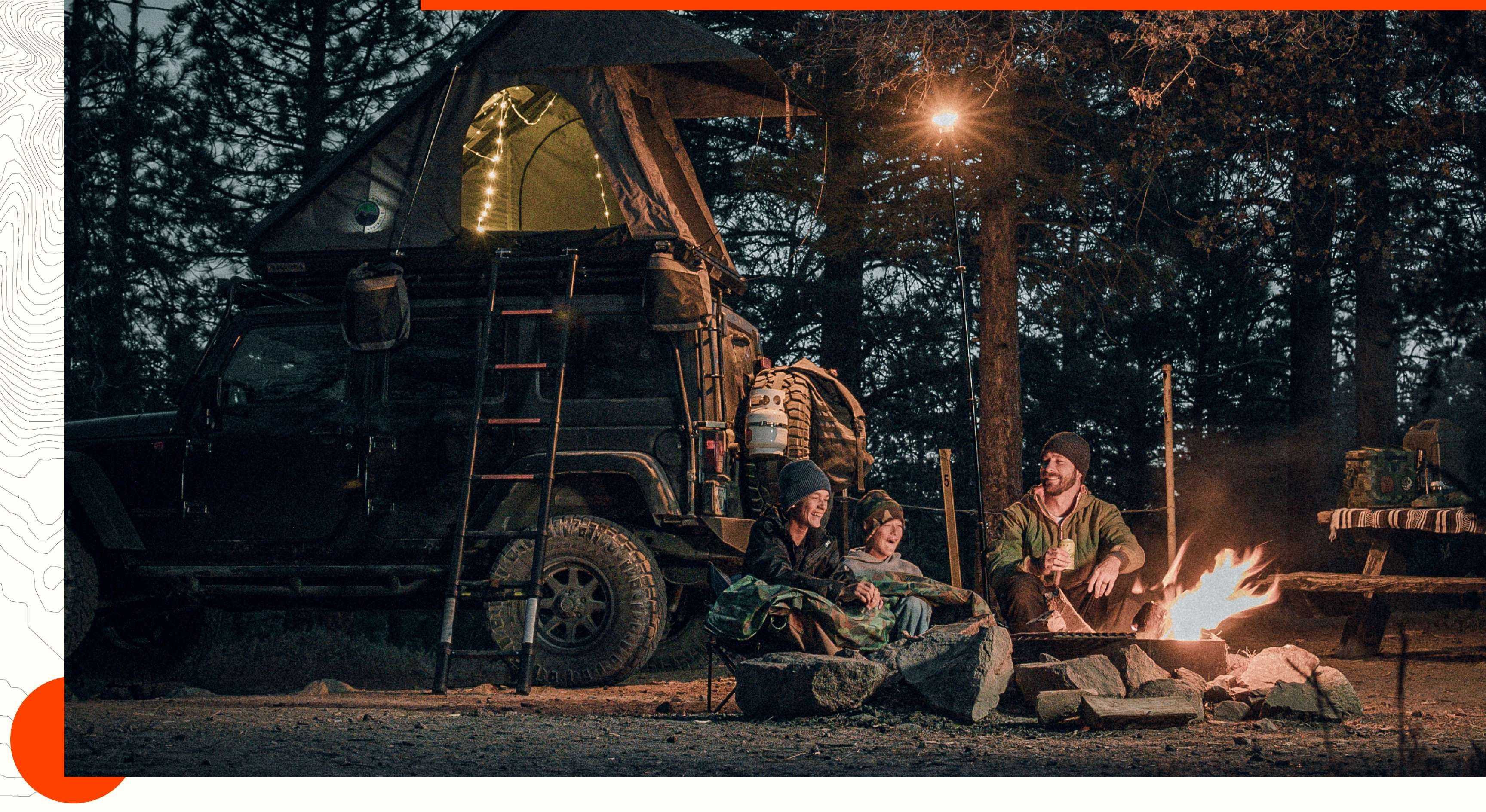A father and two boys sit around a campfire