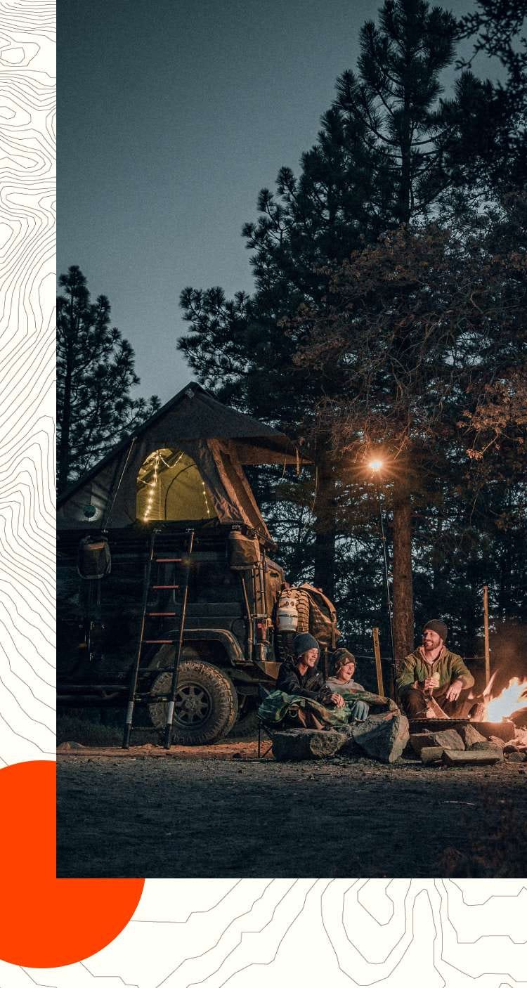 A father and two boys sit around a campfire