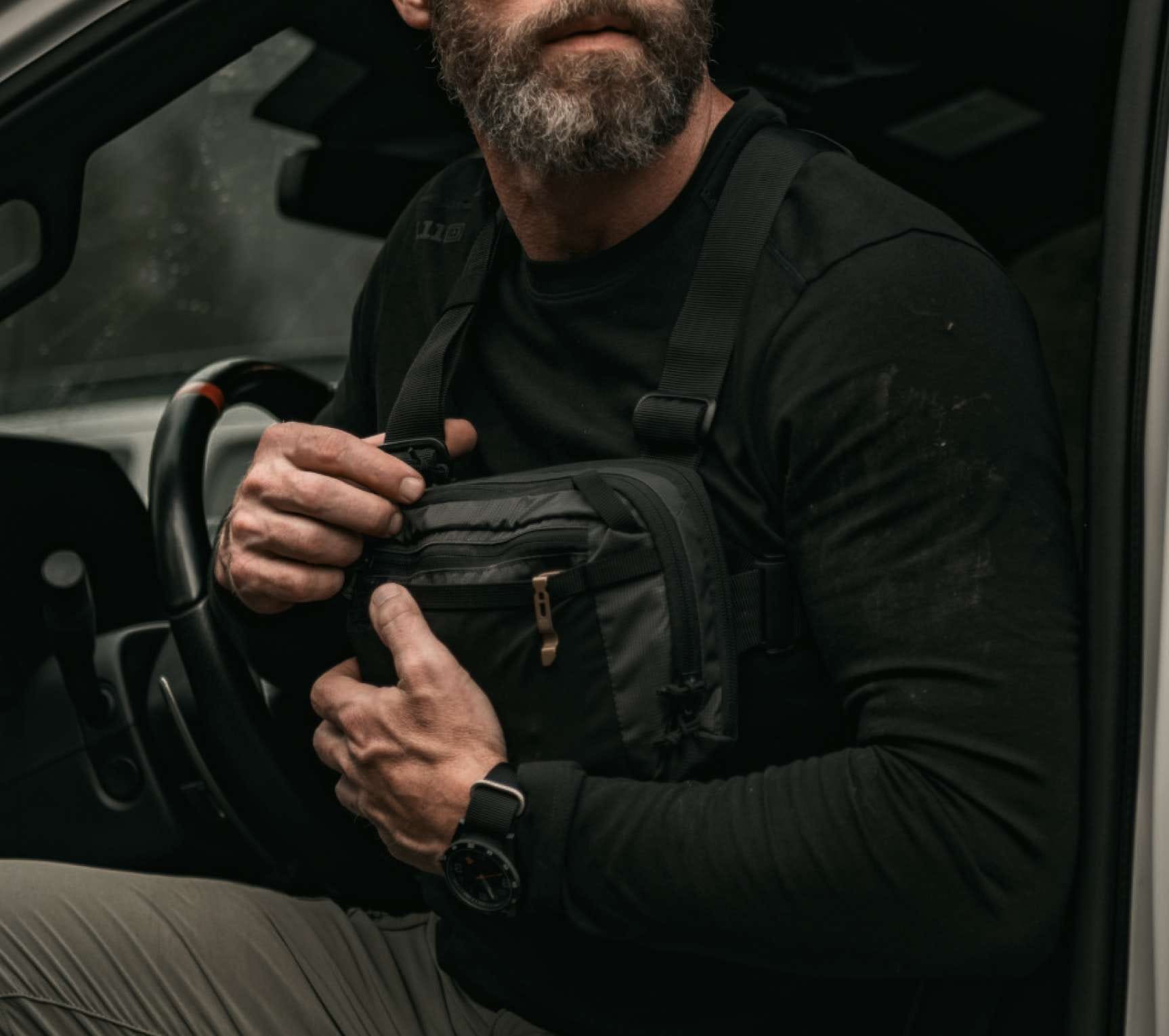 Man unzips a chest pack he's wearing on his chest