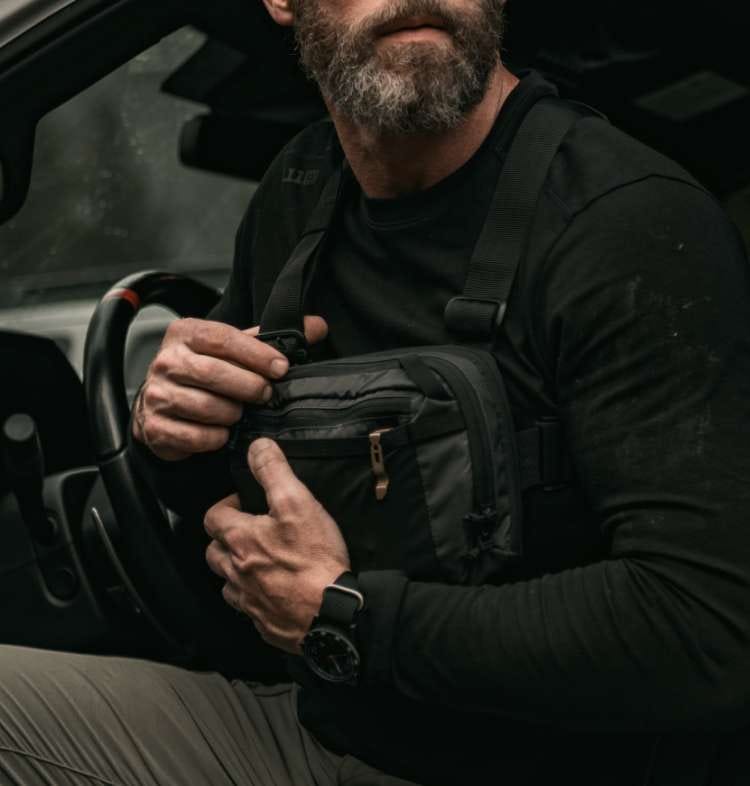 Man unzips a chest pack he's wearing on his chest