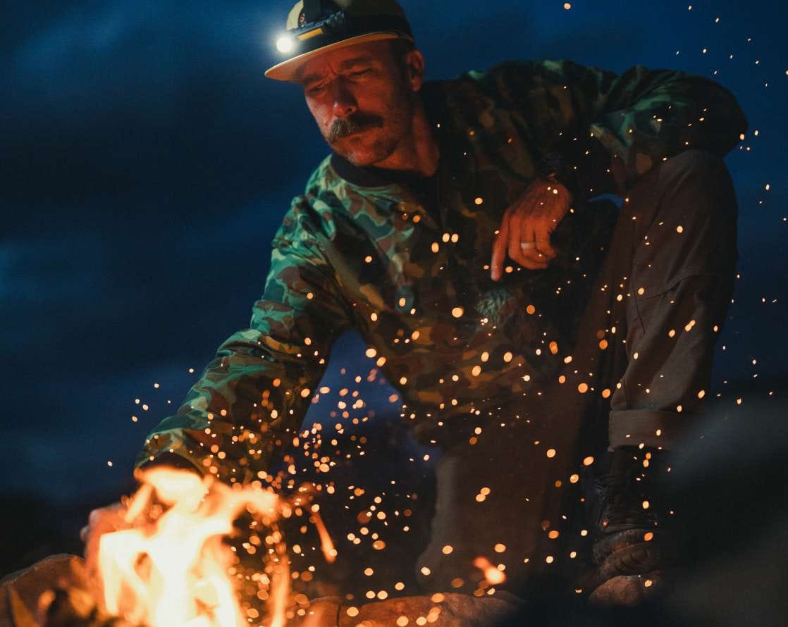 Man tends to a fire outside
