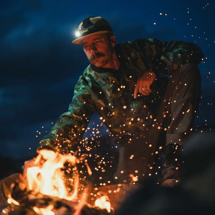 Man tends to a fire outside