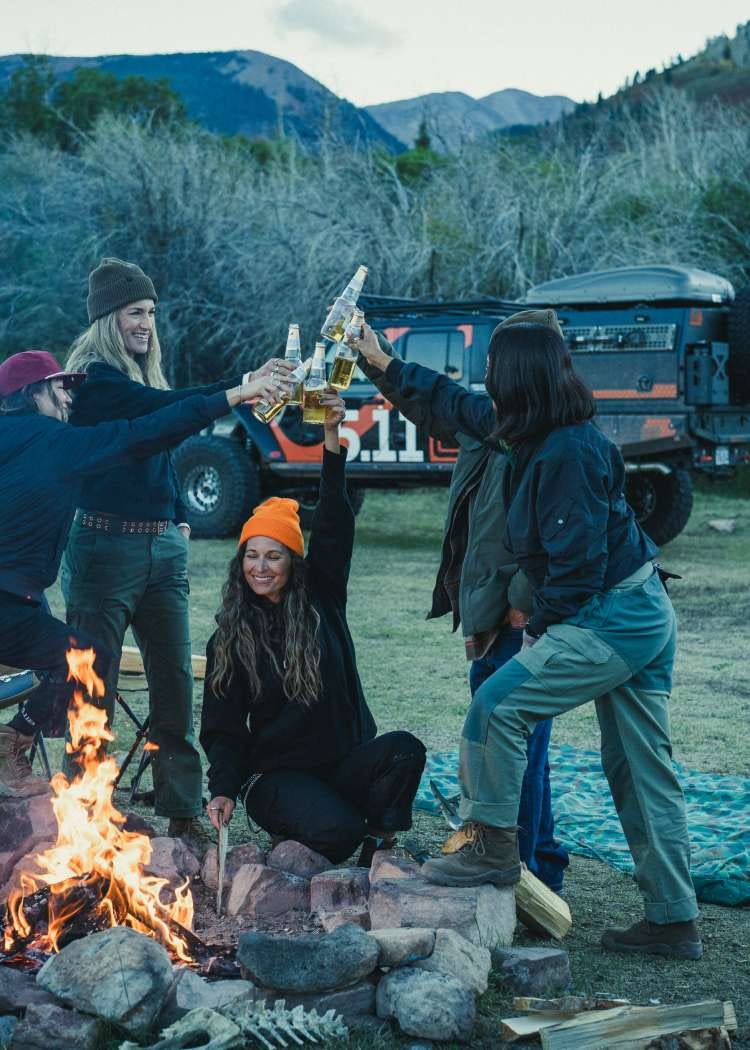 Group of men and women cheers around a campfire