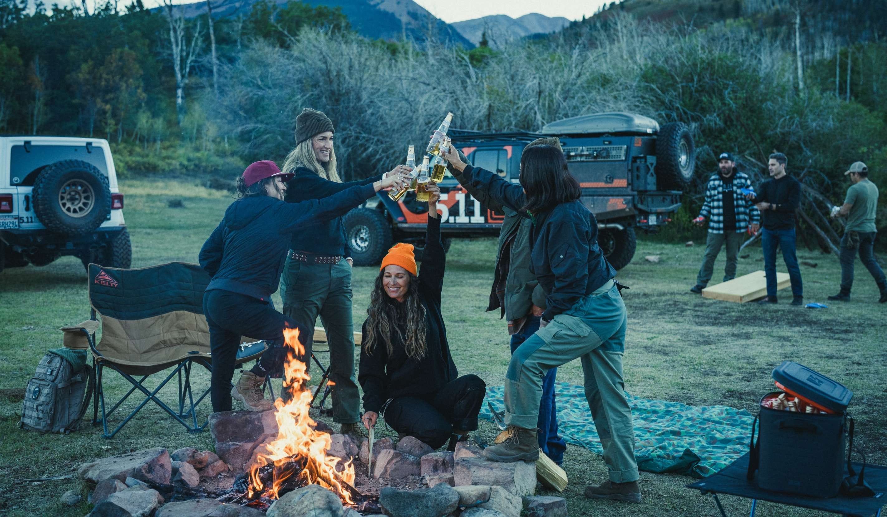 Group of men and women cheers around a campfire
