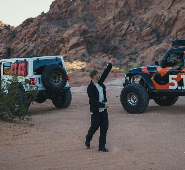 Man wearing 5.11 apparel walks around a desert landscape with off road vehicles