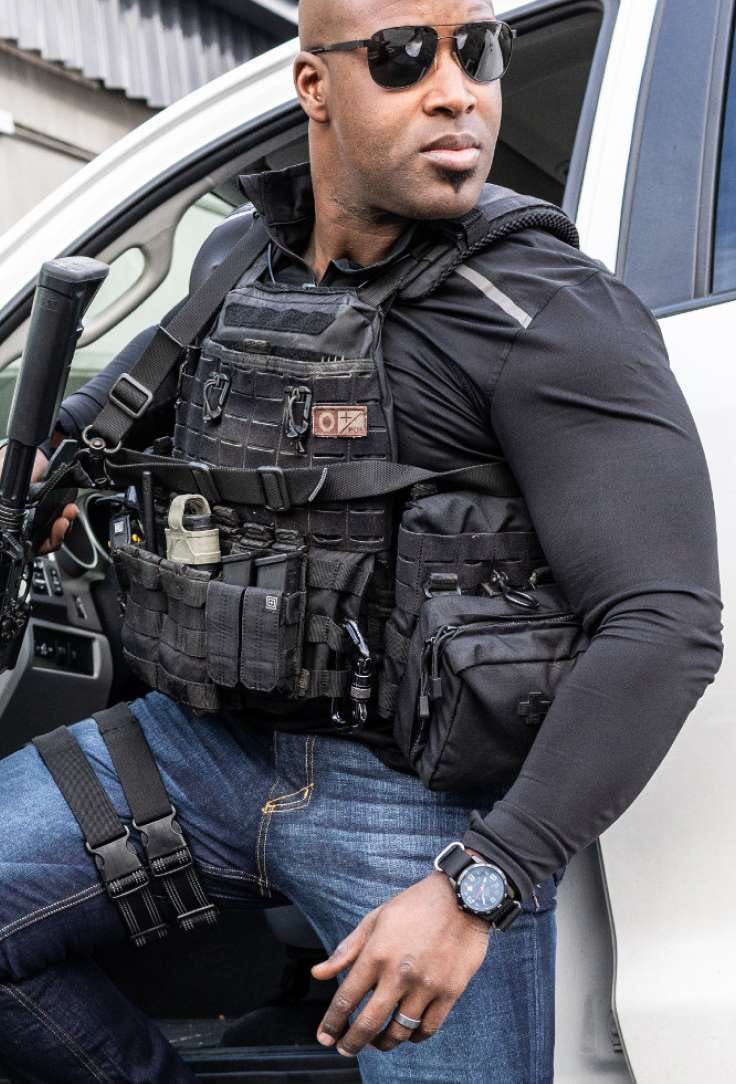 Man gets out of a vehicle wearing a plate carrier and gear