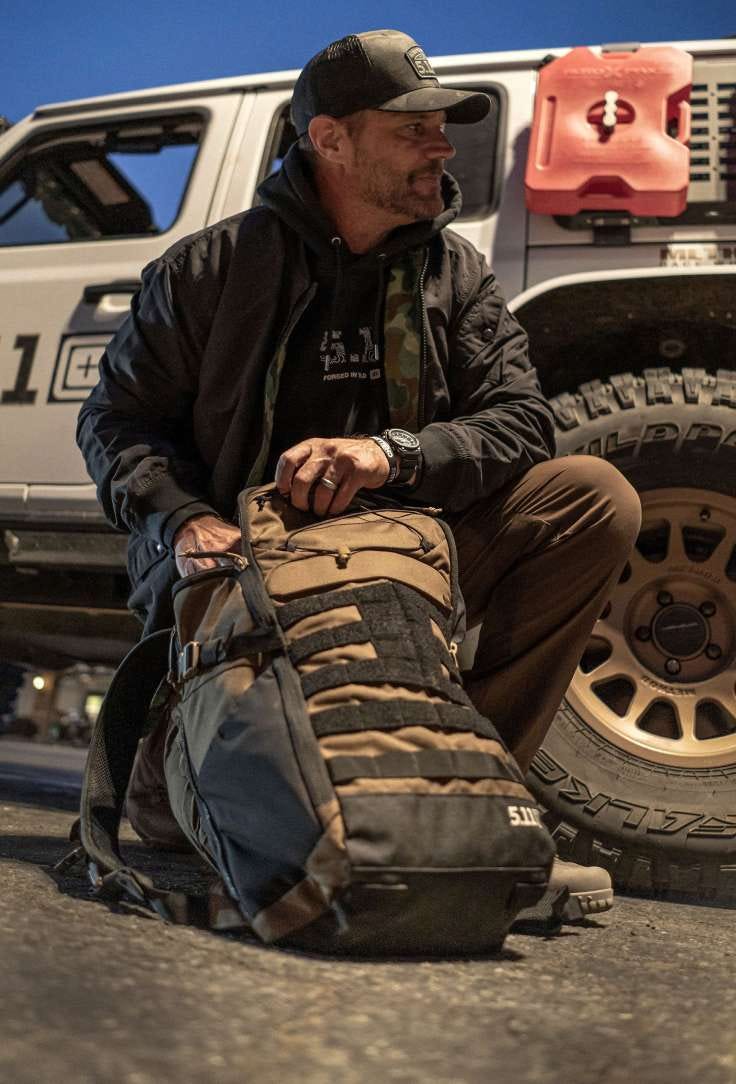 Man kneeling in front of a car loading up a MVR backpack