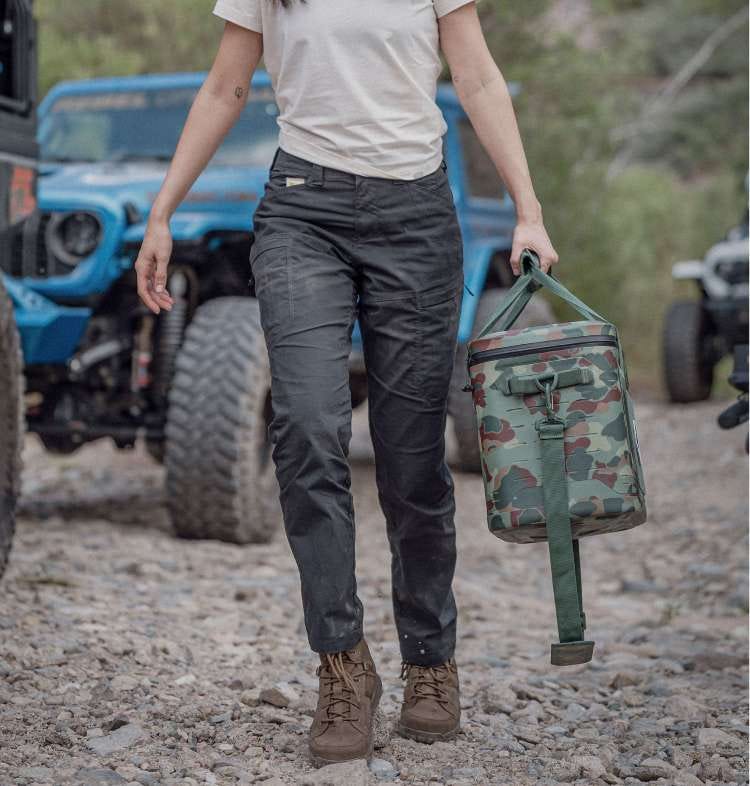 Woman walking in black pants holding a cooler