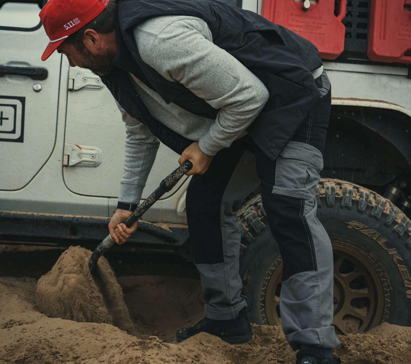 Man wearing khaki pants digging in dirt