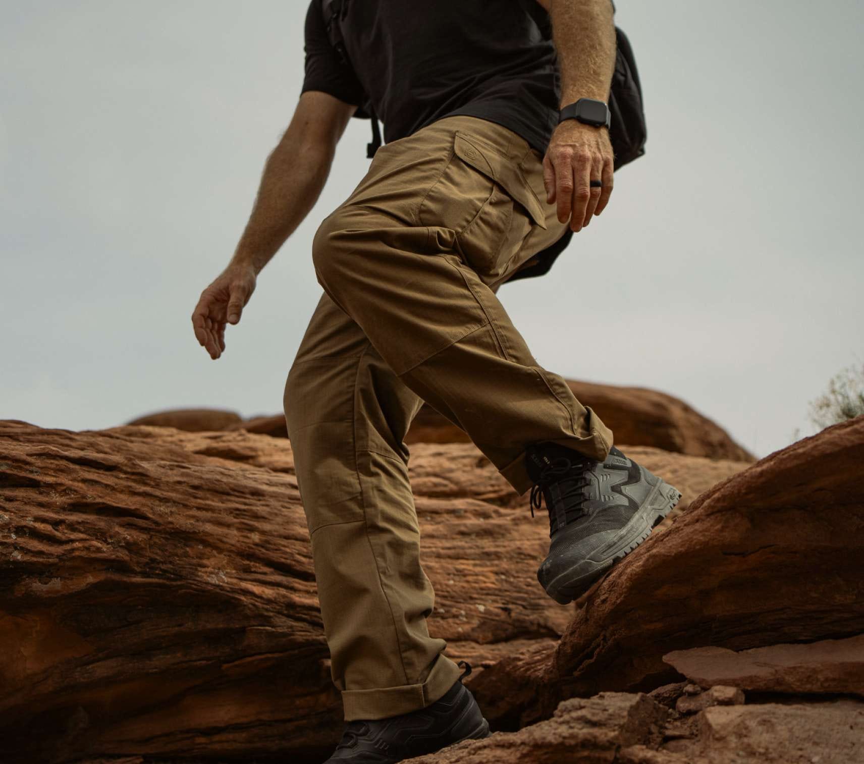 Man wearing khaki pants walking on red rock