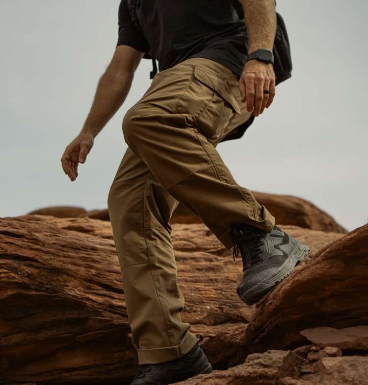 Man wearing khaki pants walking on red rock