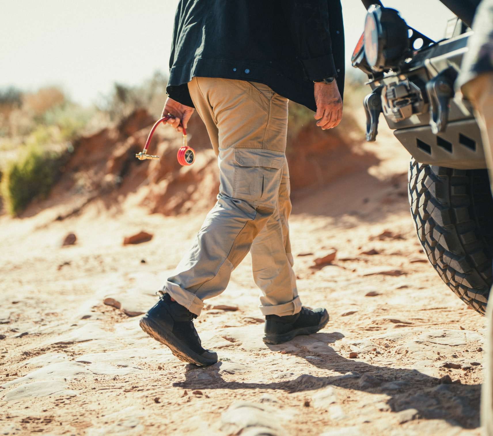 Man wearing khaki pants walking on sand