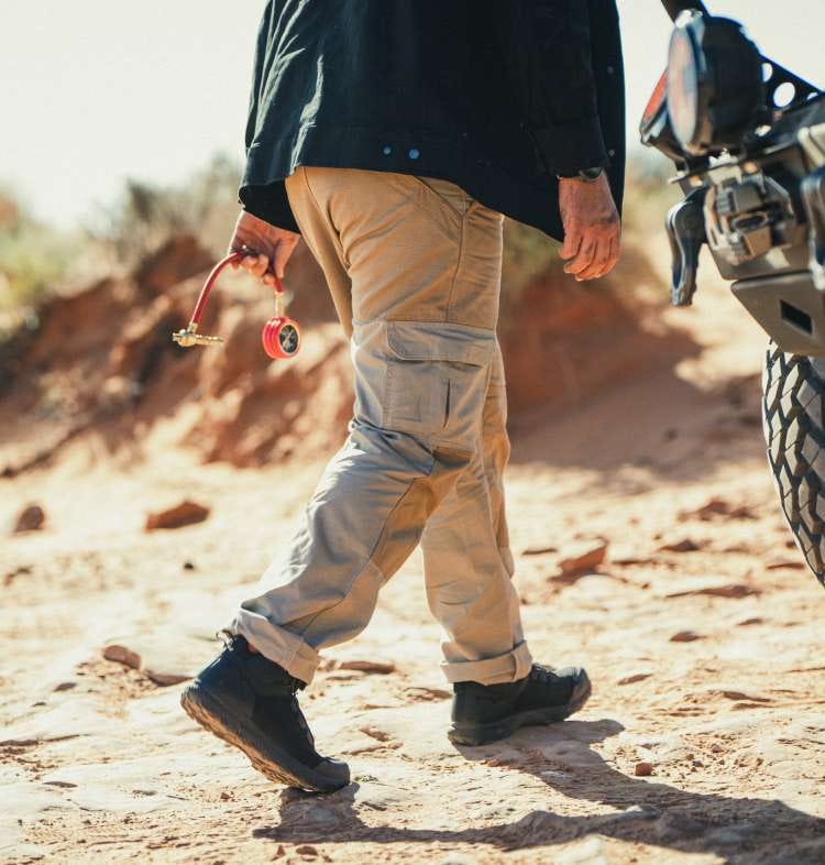 Man wearing khaki pants walking on sand
