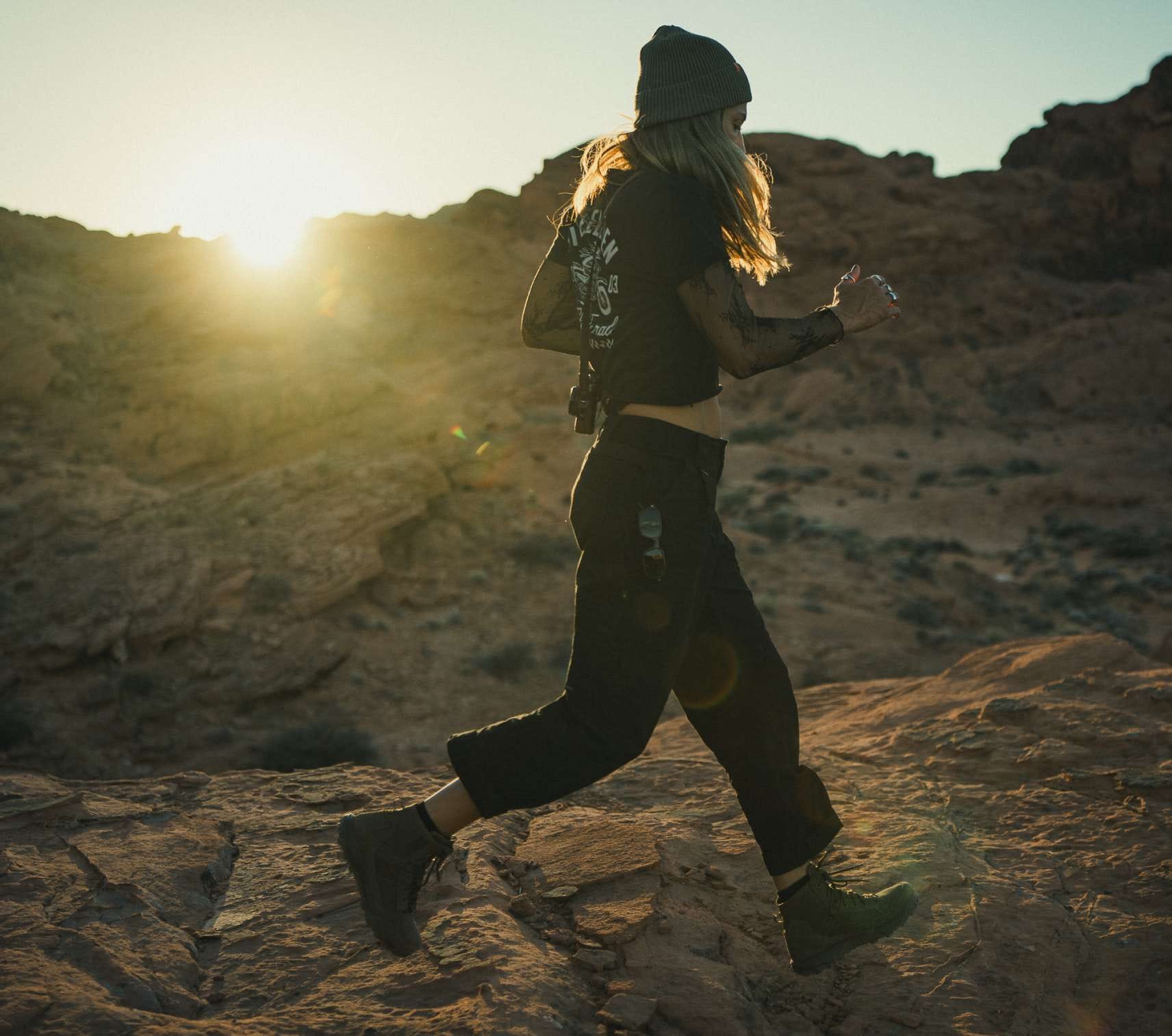 Women wearing black tactical pants running across rocks