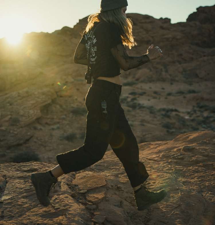 Women wearing black tactical pants running across rocks