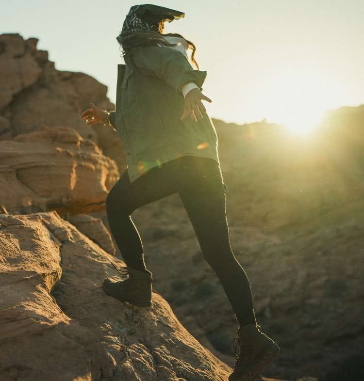 Woman wearing leggings walking up rocks 