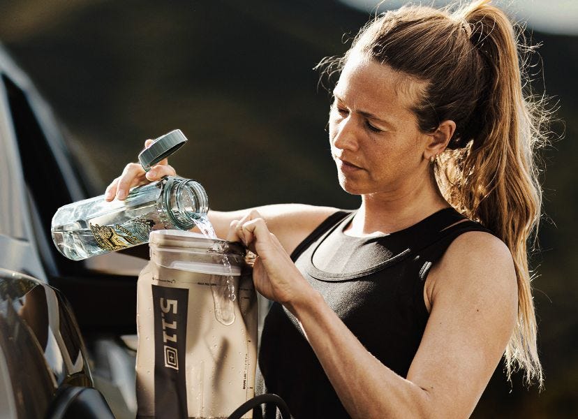 Woman pours water into a 5.11 2L hydration bladder that fits into CloudStryke