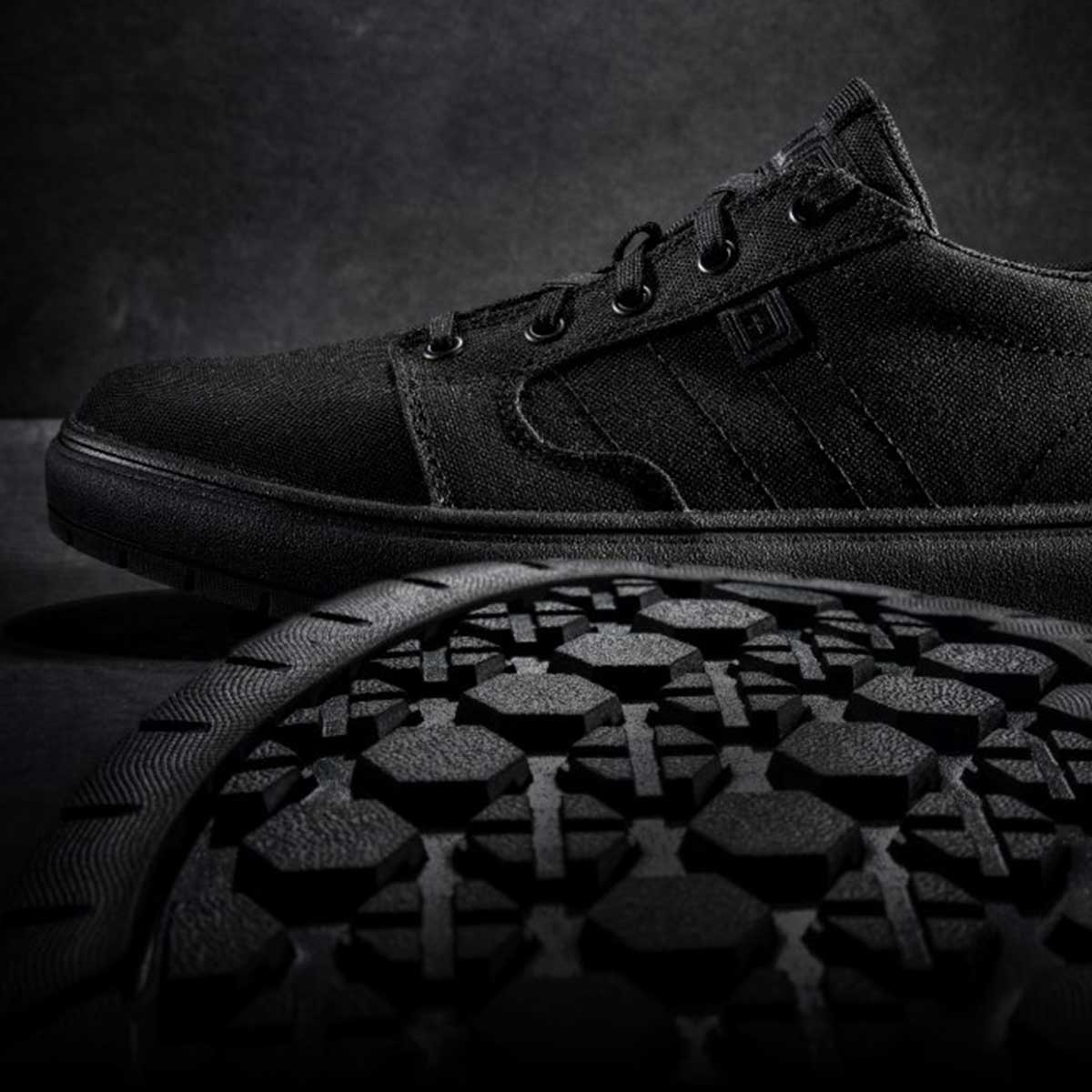 Black sneakers in front of a black background.
