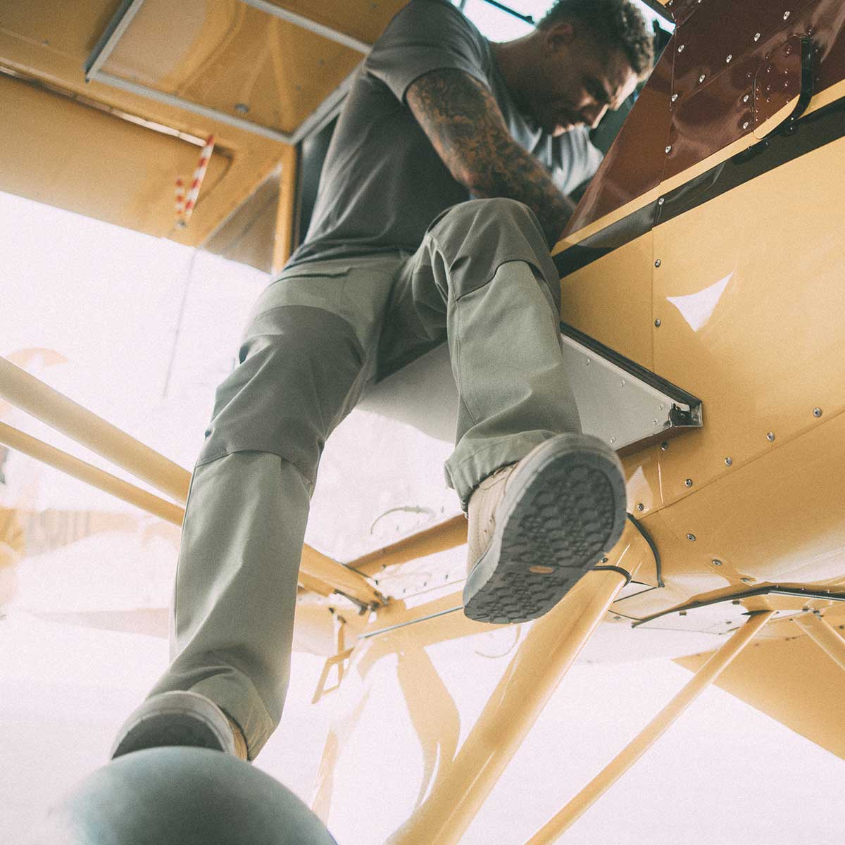 Man sitting in the opening of an airplane fixing something.
