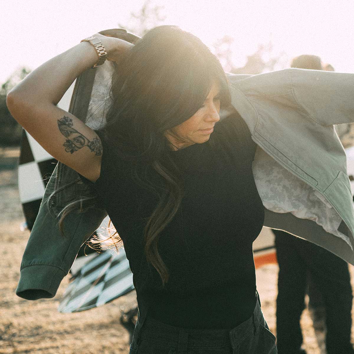 Woman wearing black t-shirt putting on a jacket.
