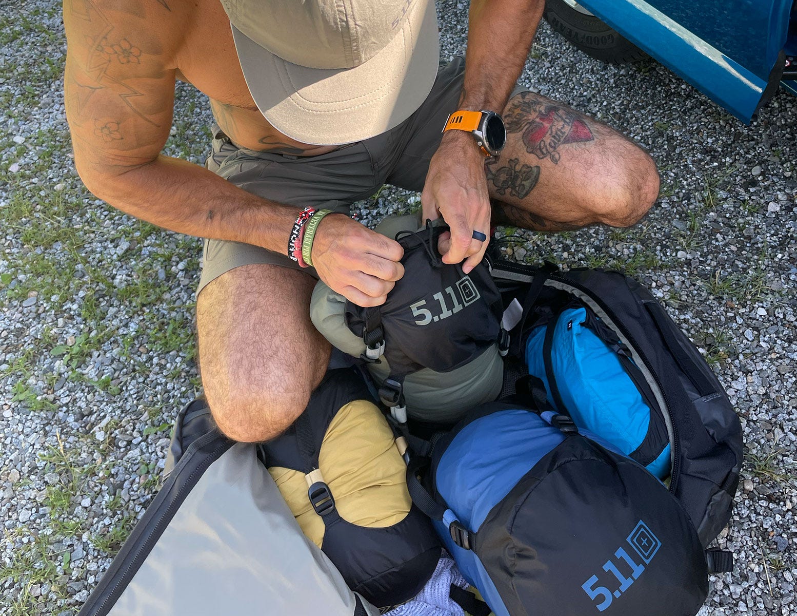 L’alpinista Luca Fois in piedi su una montagna, con indosso abbigliamento 5.11 Tactical Seduto a terra mentre prepara la sua attrezzatura riponendola nei sacchi di compressione 5.11.